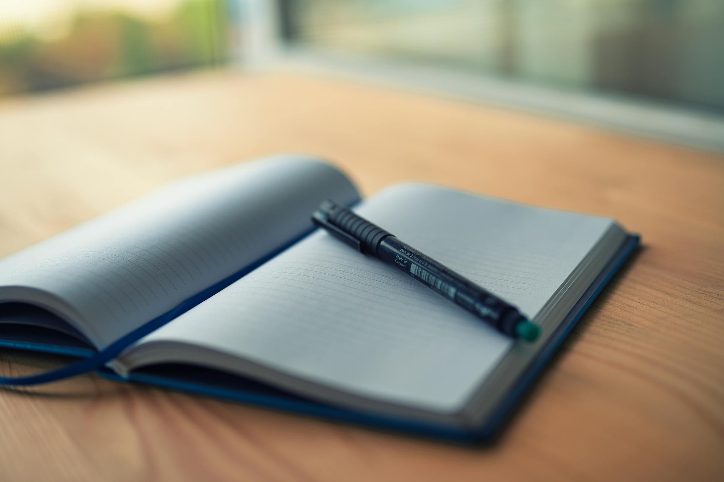 Offenes Notizbuch mit Stift auf einem Holztisch im warmen Fensterlicht