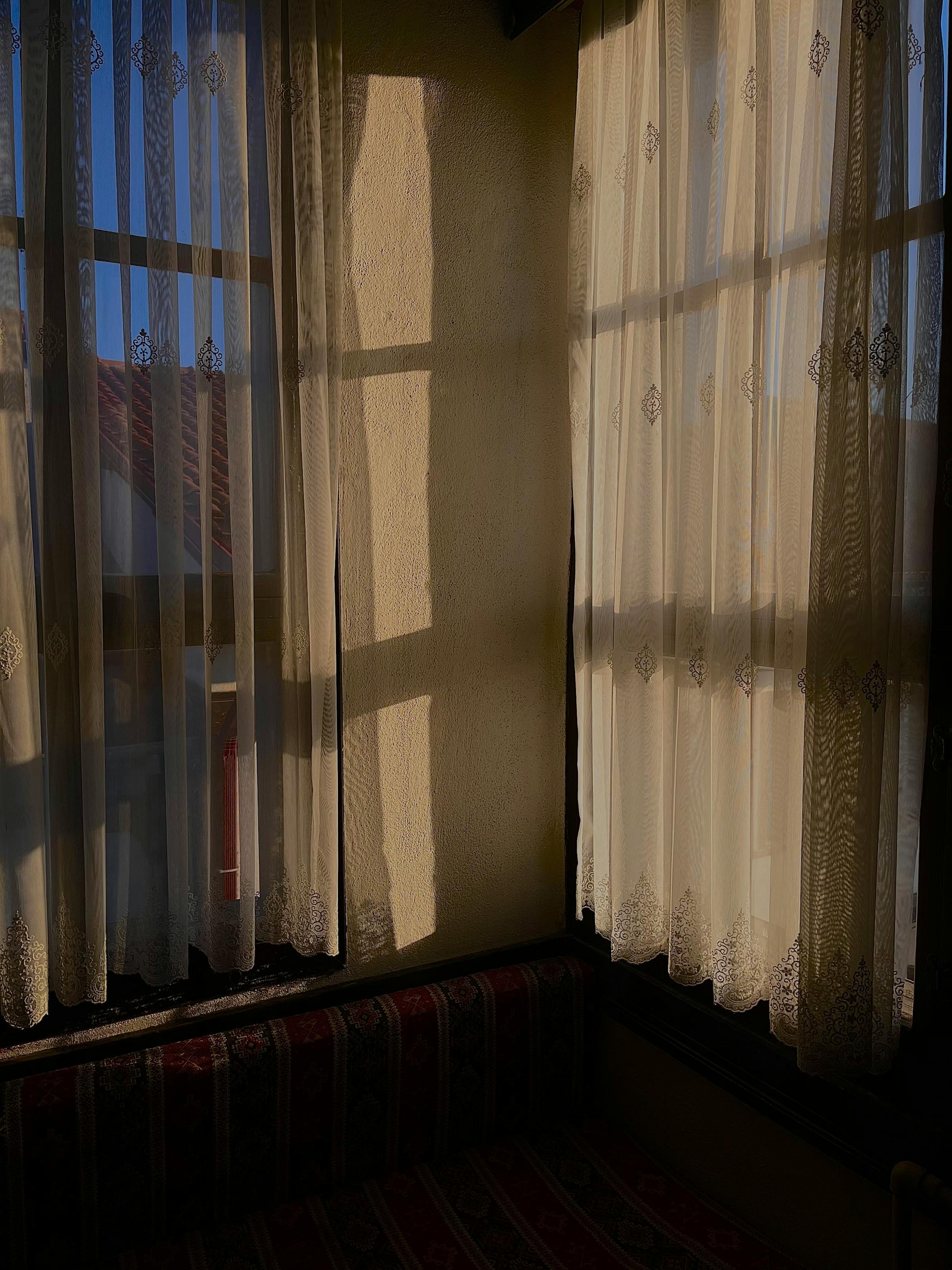 Warmes Morgenlicht durch bestickte Gardinen in einer ruhigen Ecke